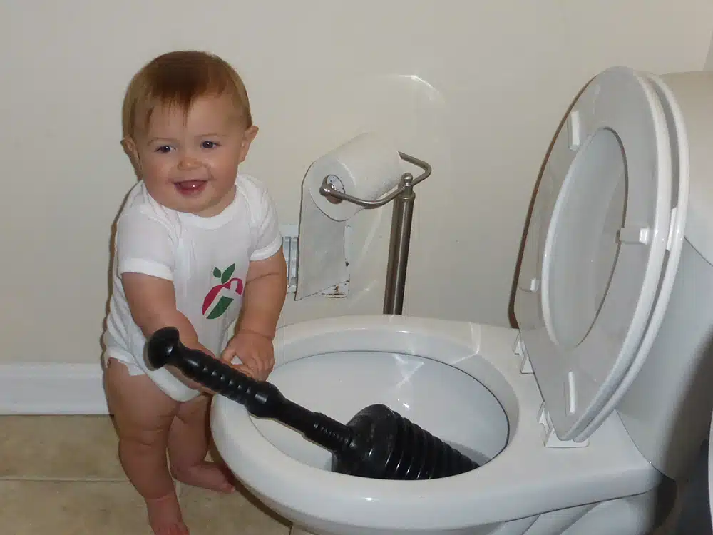 Toddler holding plunger in toilet in residential home in Warrenton, VA.