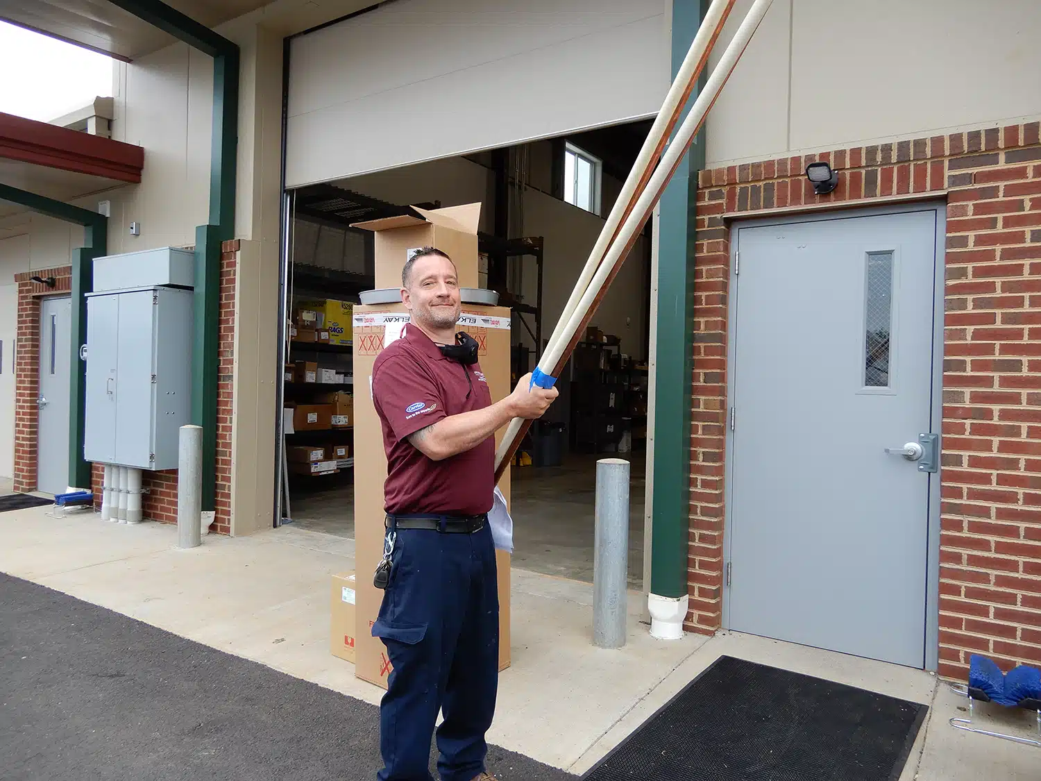 Appleton Campbell plumber carrying pipe outside of warehouse in Warrenton, VA.
