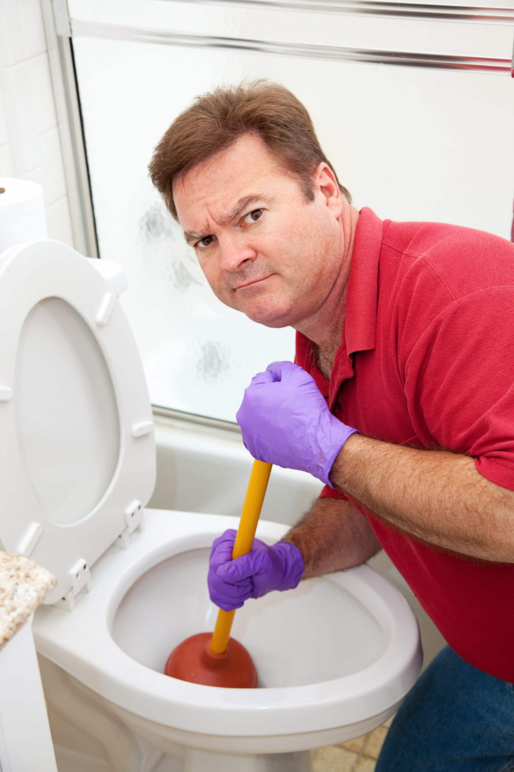 Man is not happy about having to use a plunger to unclog the toilet.